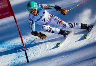 Competitive downhill skier racing towards flag