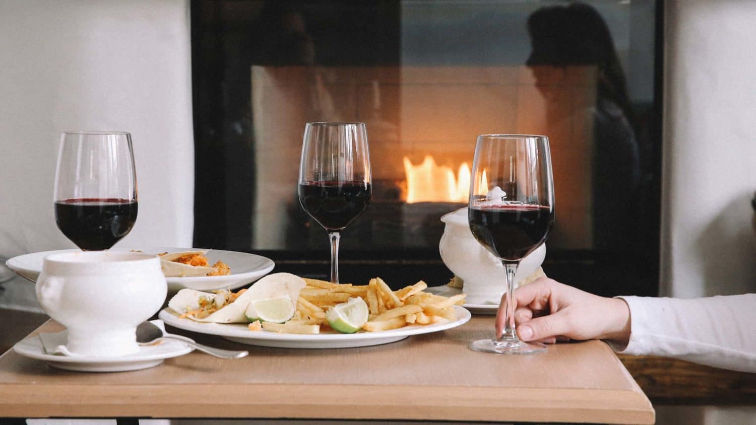 small table in front of fireplace, with entrees and glasses of wine