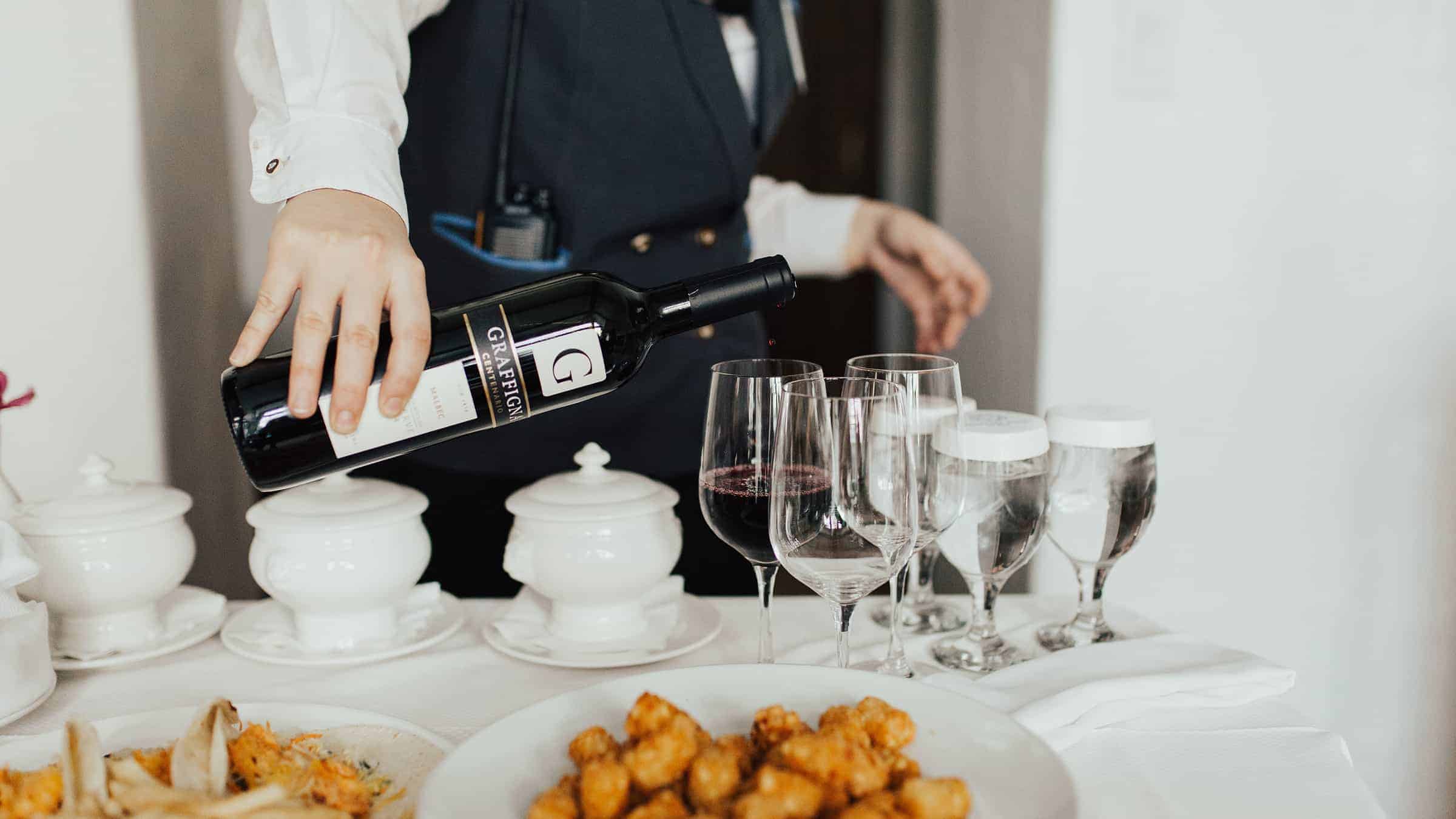 ROOMSERVICE-3 Server pouring wine into glasses