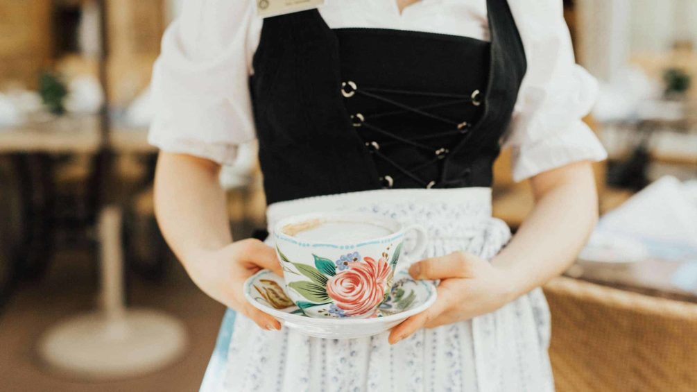 woman wearing dirndl holding cup of coffee on saucer