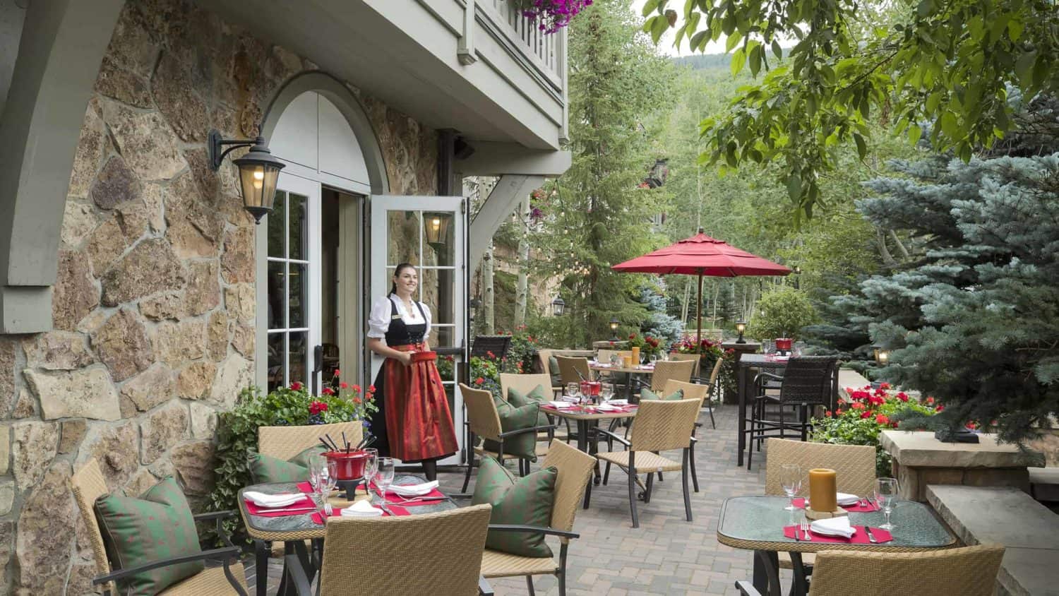 Sonnenalp Swiss Chalet outdoor patio with tables, chairs, and woman wearing dirndl carrying pot