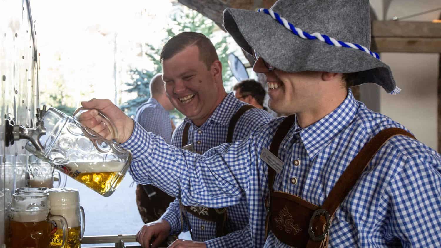 Men eraring leather suspenders, pourng beers into large mugs