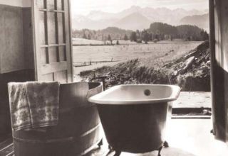 Room with two tubs, doors open, and view of trees and hills
