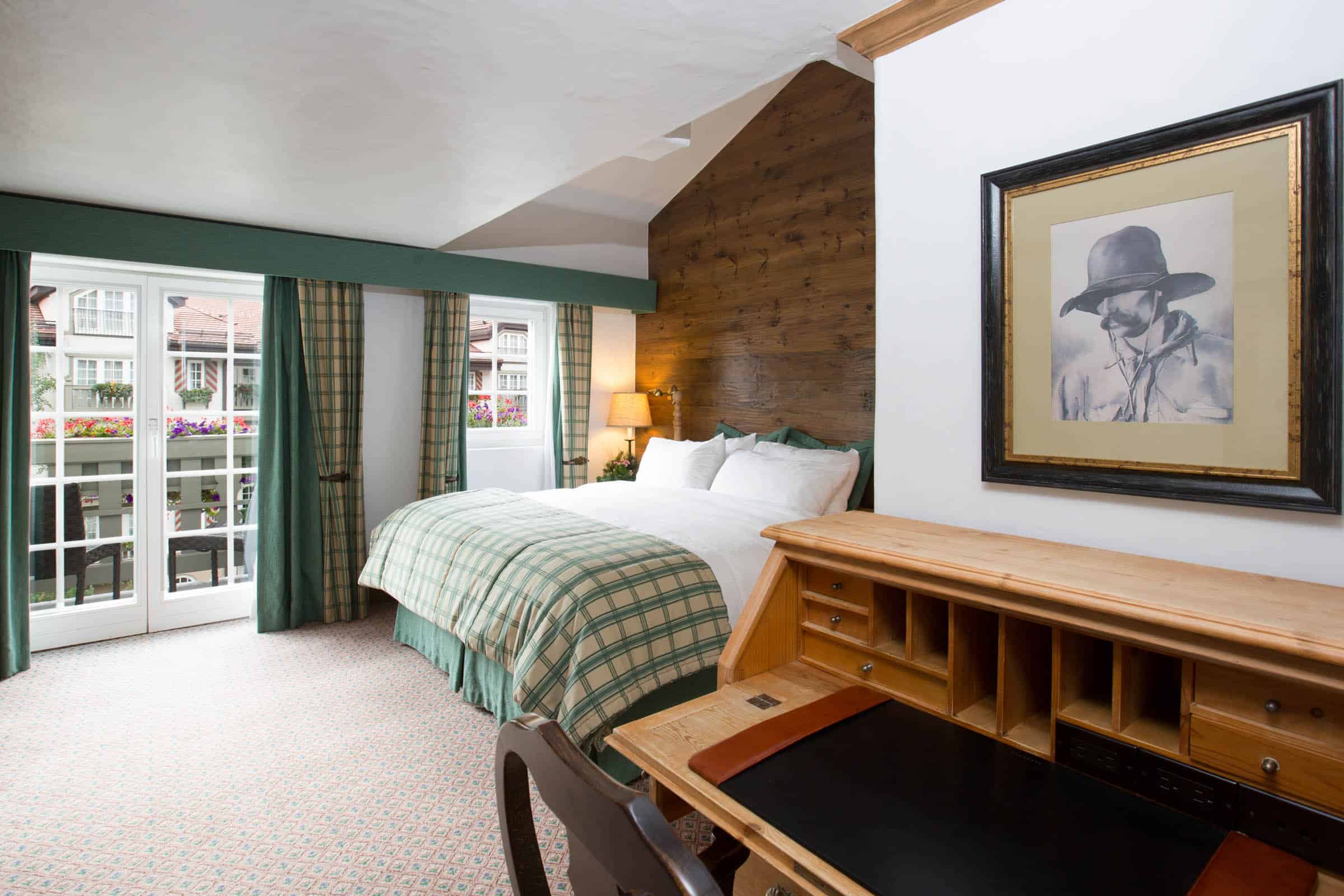 juniper room with bed, doors leading to balcony in background, desk and chair in foreground