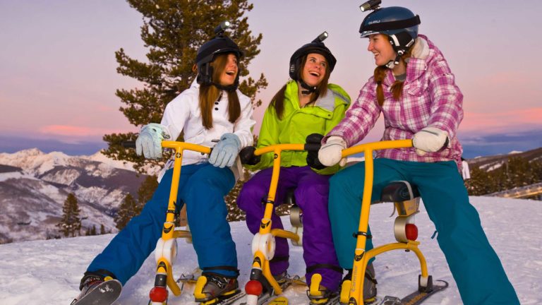 Women on snow cycles, on slopes, at dusk
