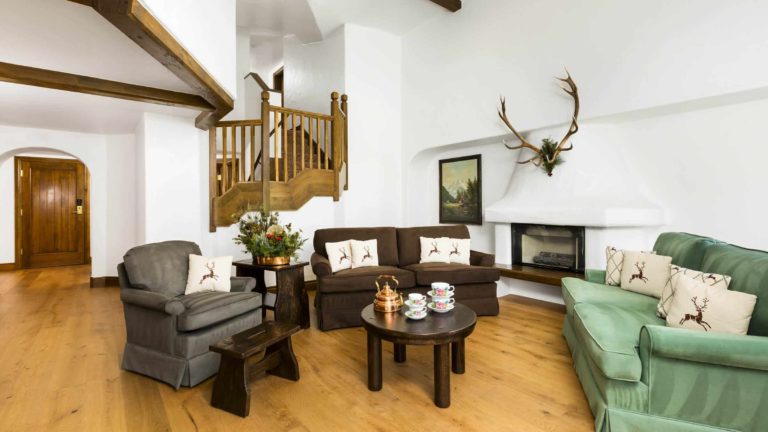 Living room with sofa, chairs, fireplace, and stairs