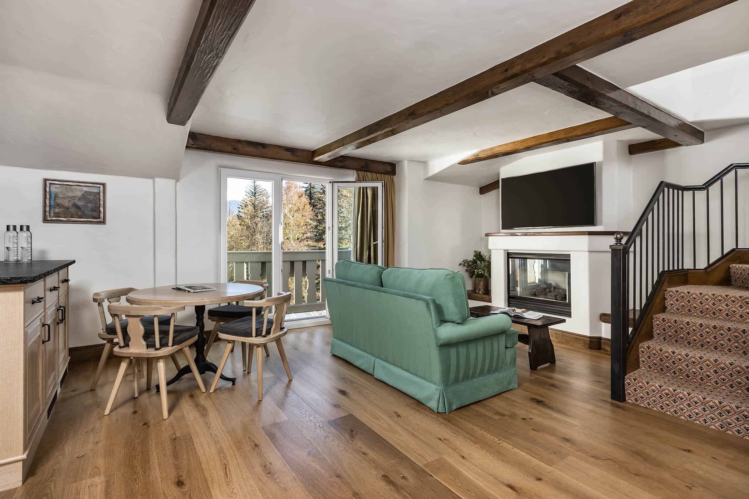 Living room with sofa, dining table, chairs, fireplace, and open door leading to balcony