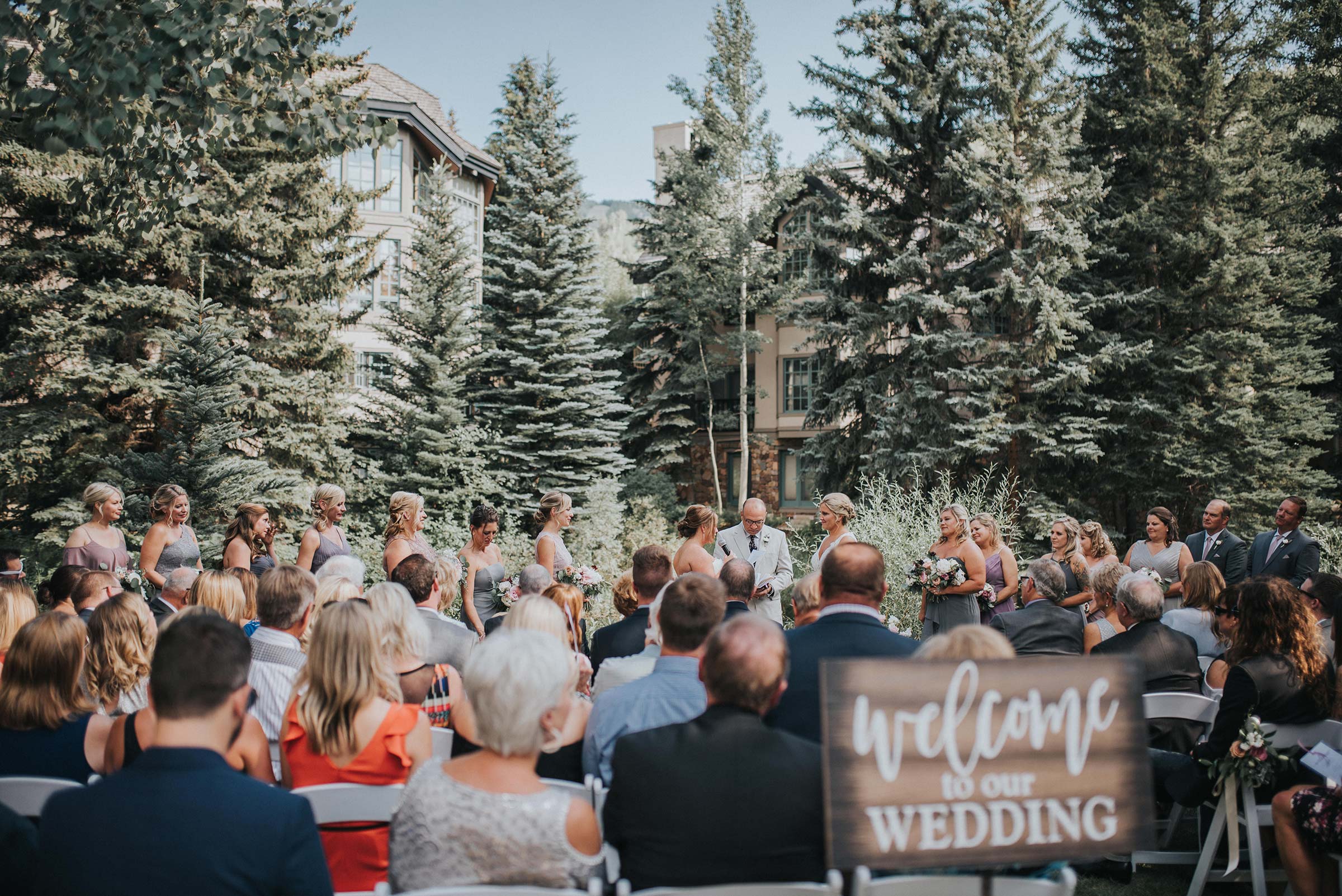 Wedding ceremony outdoors, pien trees and hotel in the background