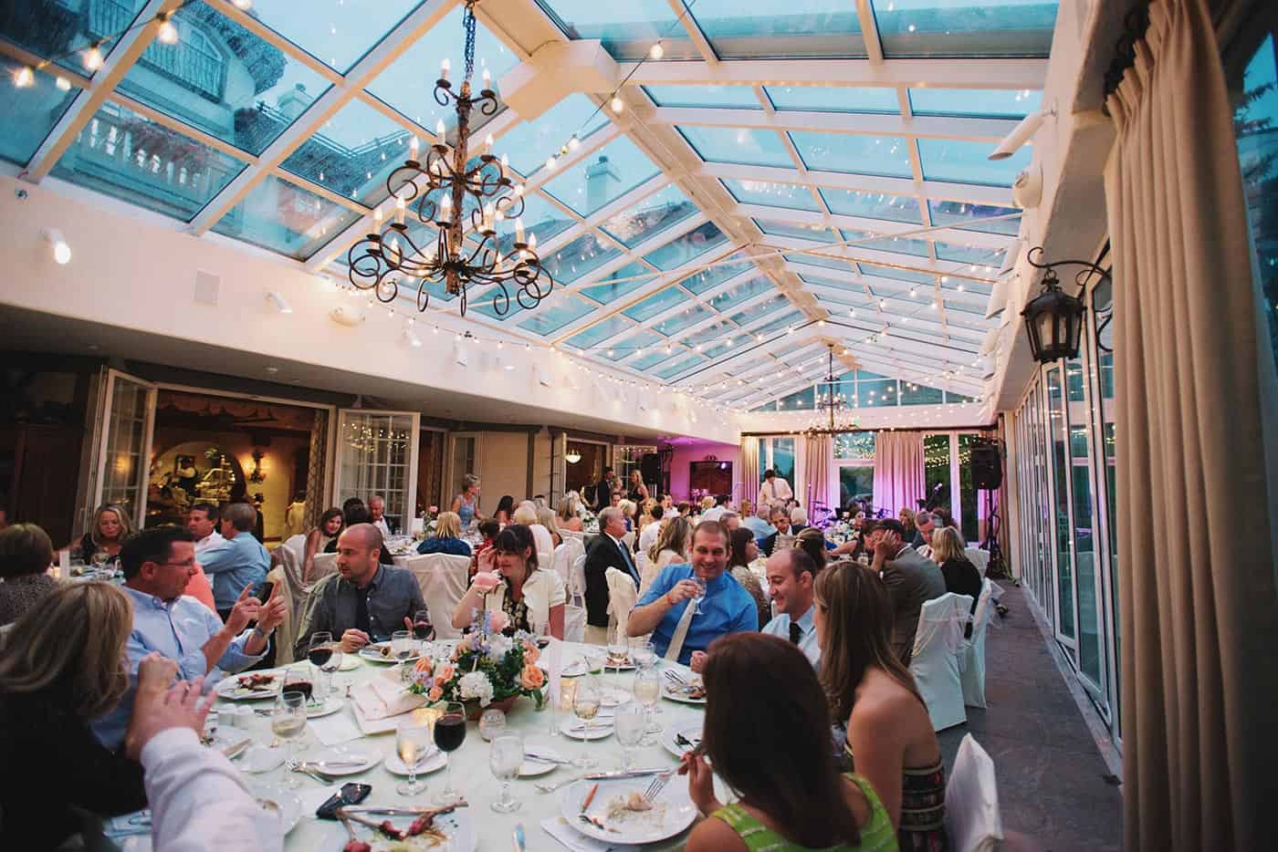 A large group of people sitting at tables under a glass roof