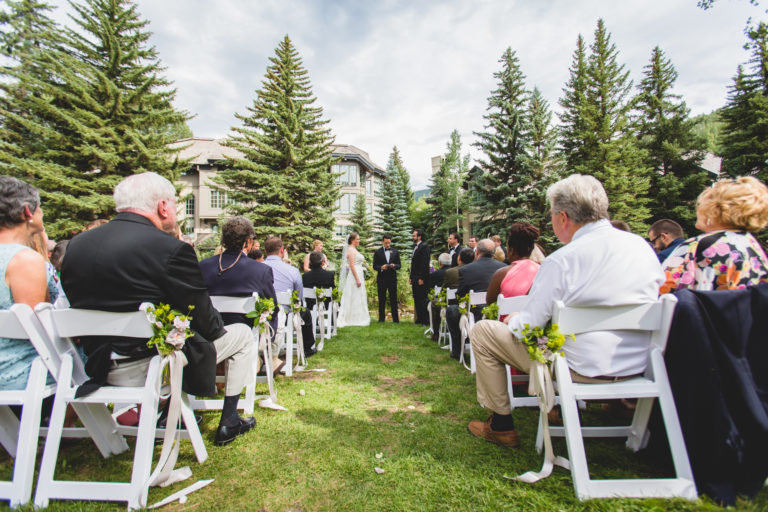 Outdoor wedding ceremony as seen from center aisle, behind seating area