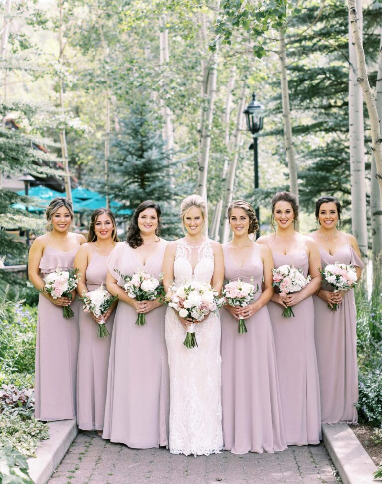 Bride in the center, bridesmaids next to her, all holding flower bouquets