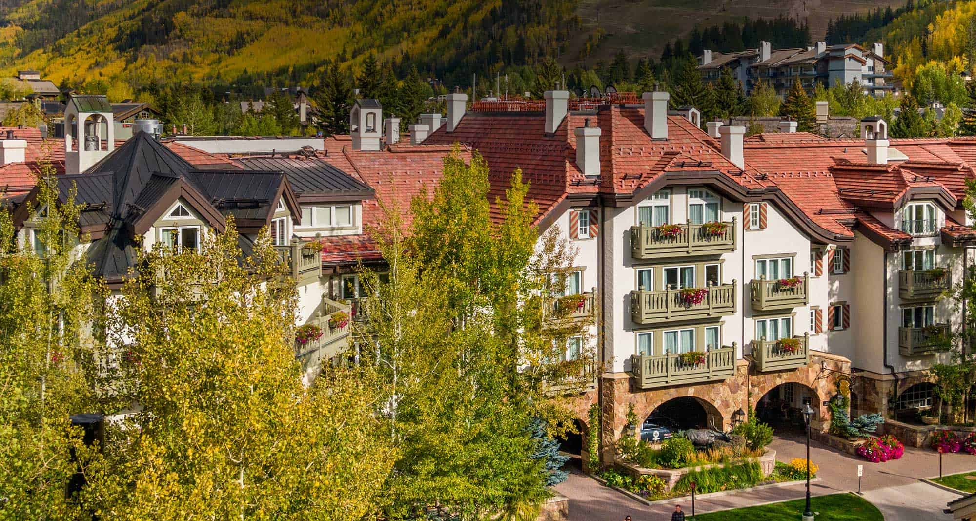 Exterior of Sonnenalp Hotel on a sunny day, hills with trees in the background