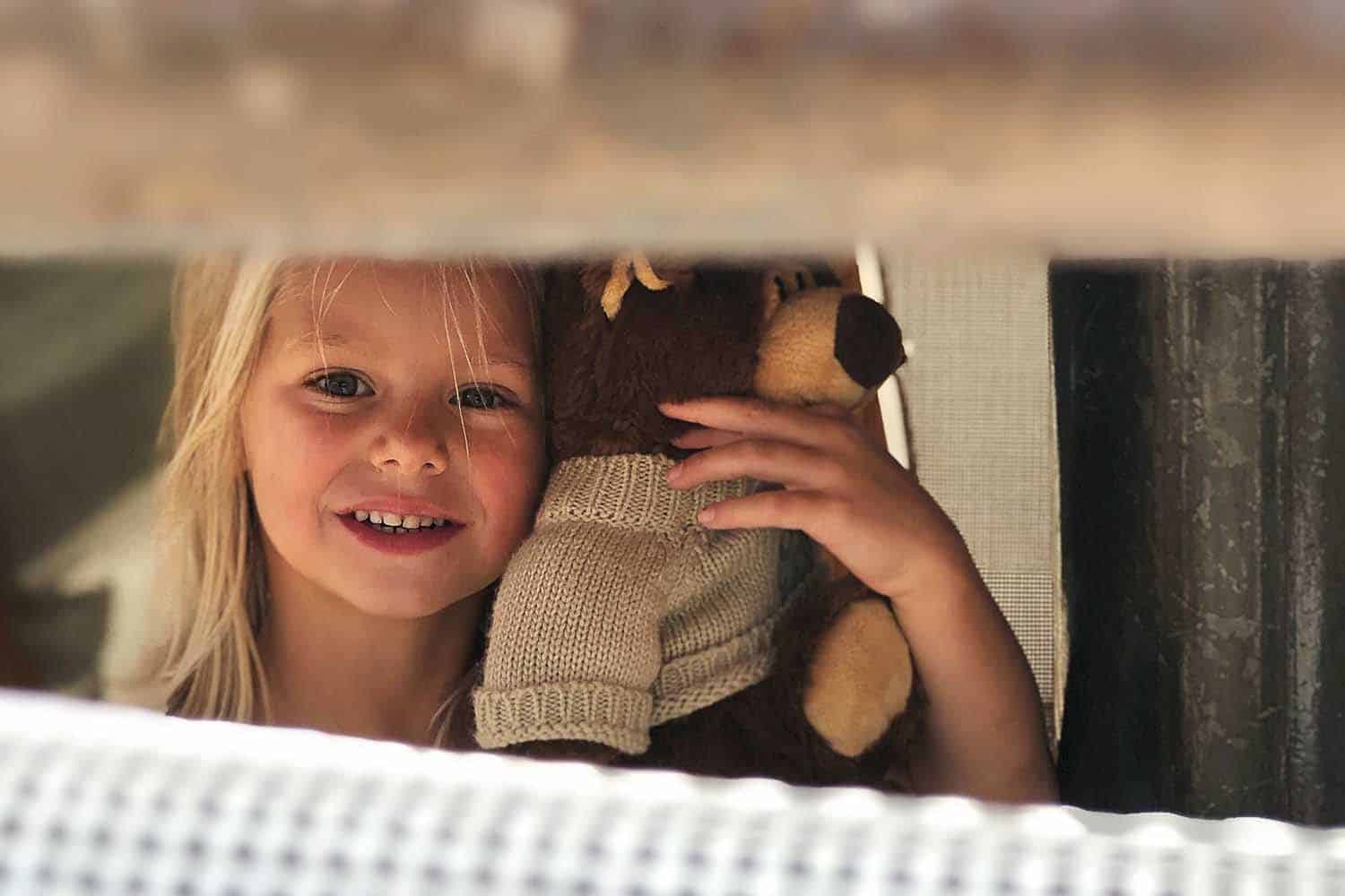 Sonnenalp-Activies-_0001_Kids Club little girl with bear Young girl smiling, holding a teddy bear to her ear