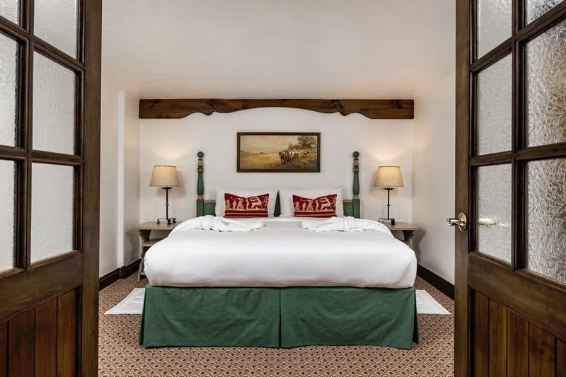 A wide view of a hotel room with a large bed, nightstands, and a painting on the wall.