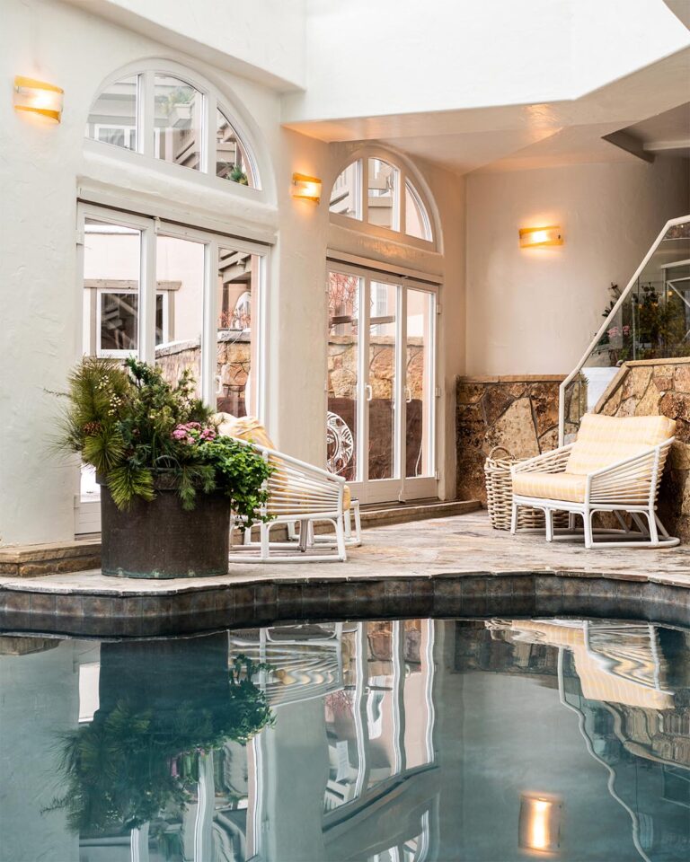 Indoor pool area with patio furniture and large glass doors leading to an outdoor area