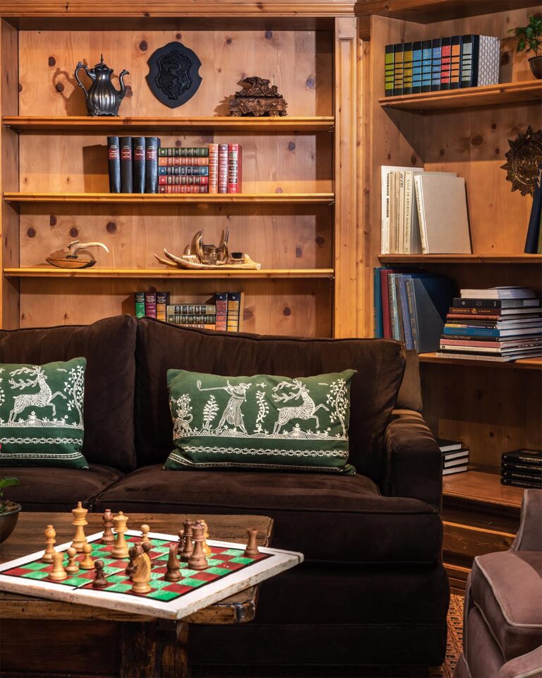 Sofa, coffee table with chessboard on foreground, and bookcase shelves in the background