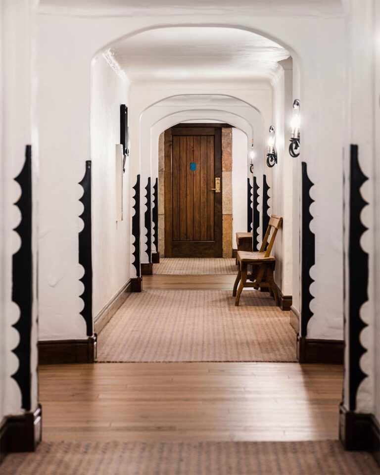 Hotel hallway with area rugs, wooden benches, and door at the end of the hallway