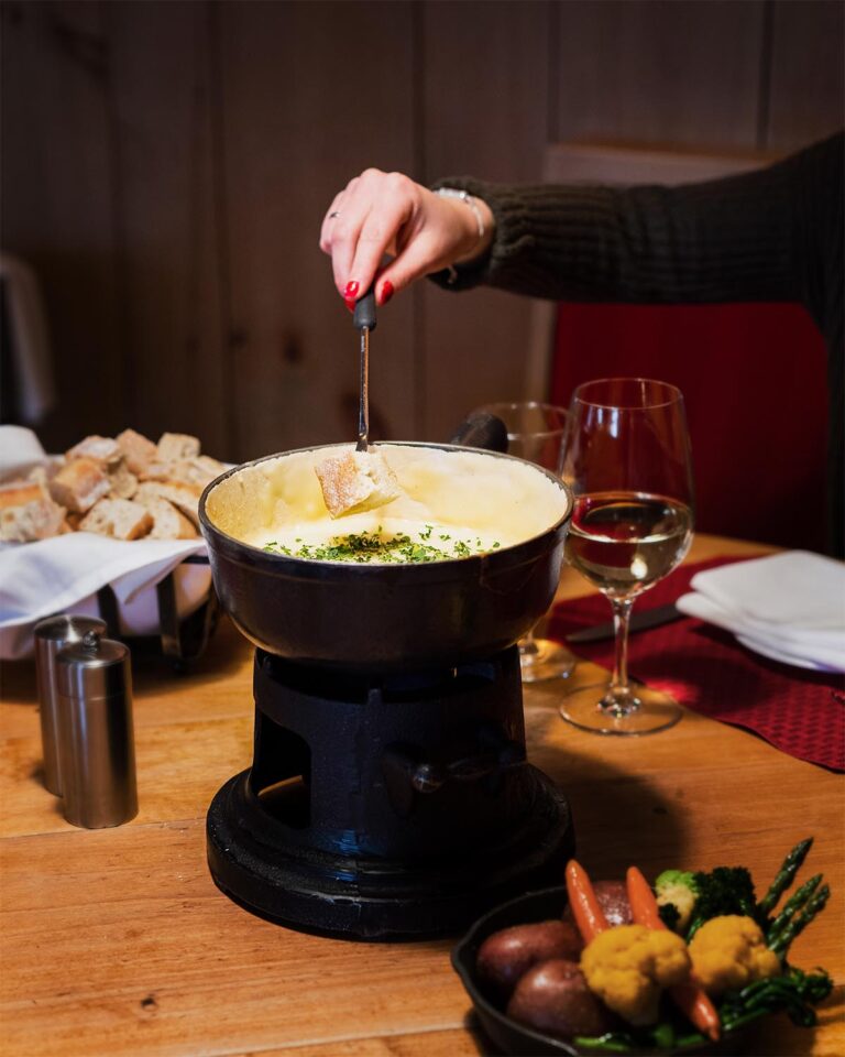 Woman dipping bread into fondue pot at table