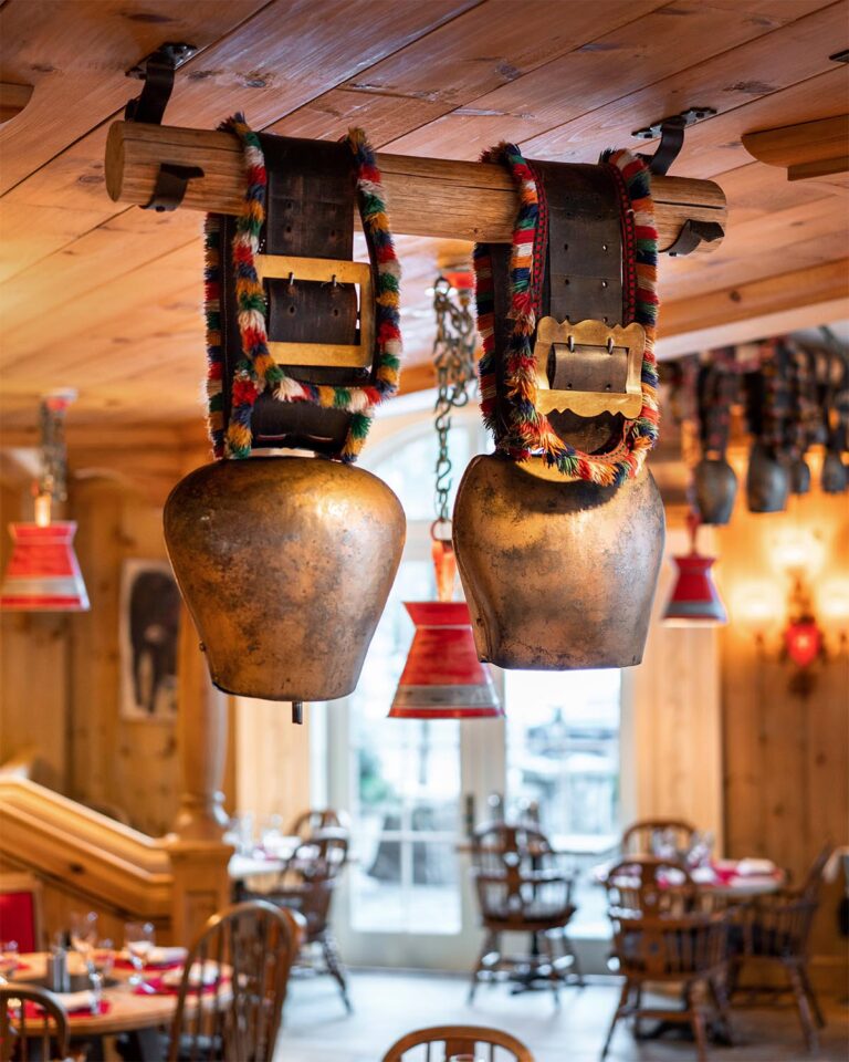 Two cowbells attached to leather belts, hanging from restaurant's dining area ceiling