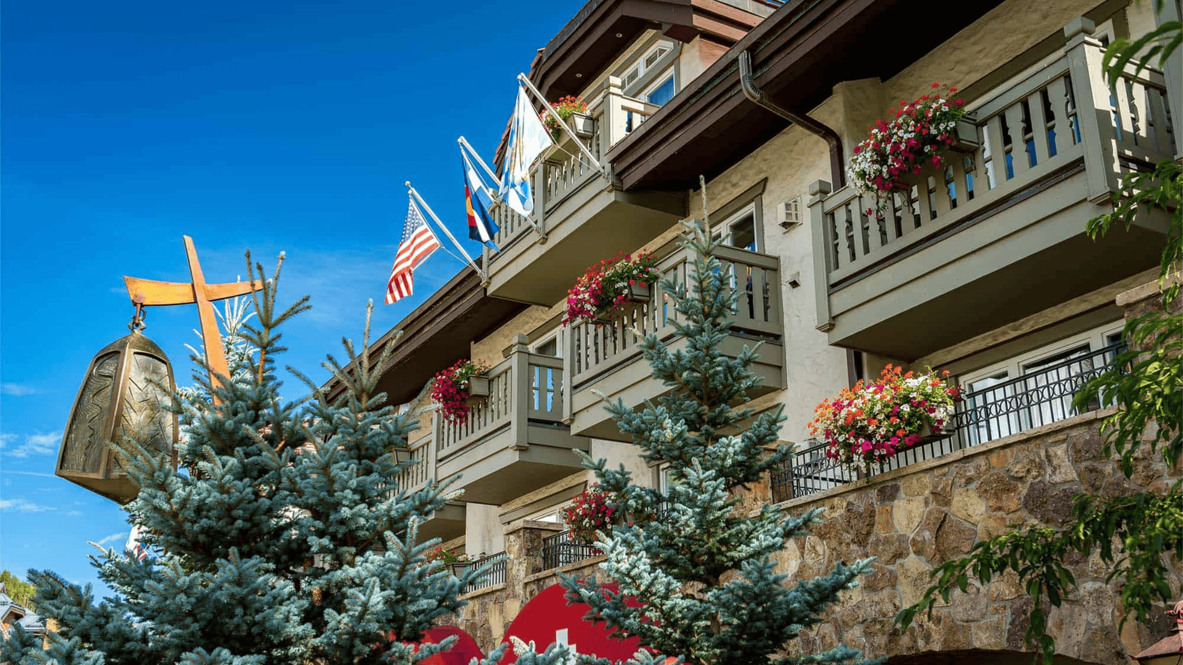 A view of the Sonnenalp balconies adorned with flower boxes set behind pine trees in Vail springtime.