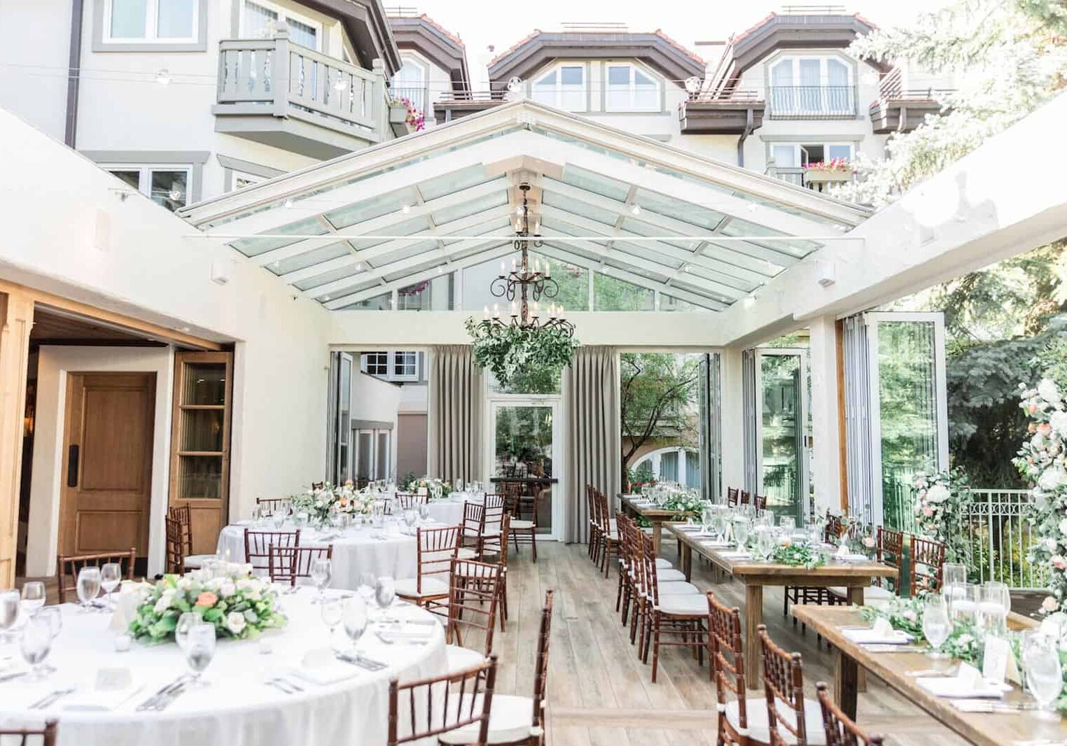 Wedding reception area with tables with placesettings, chairs, and open-air roof
