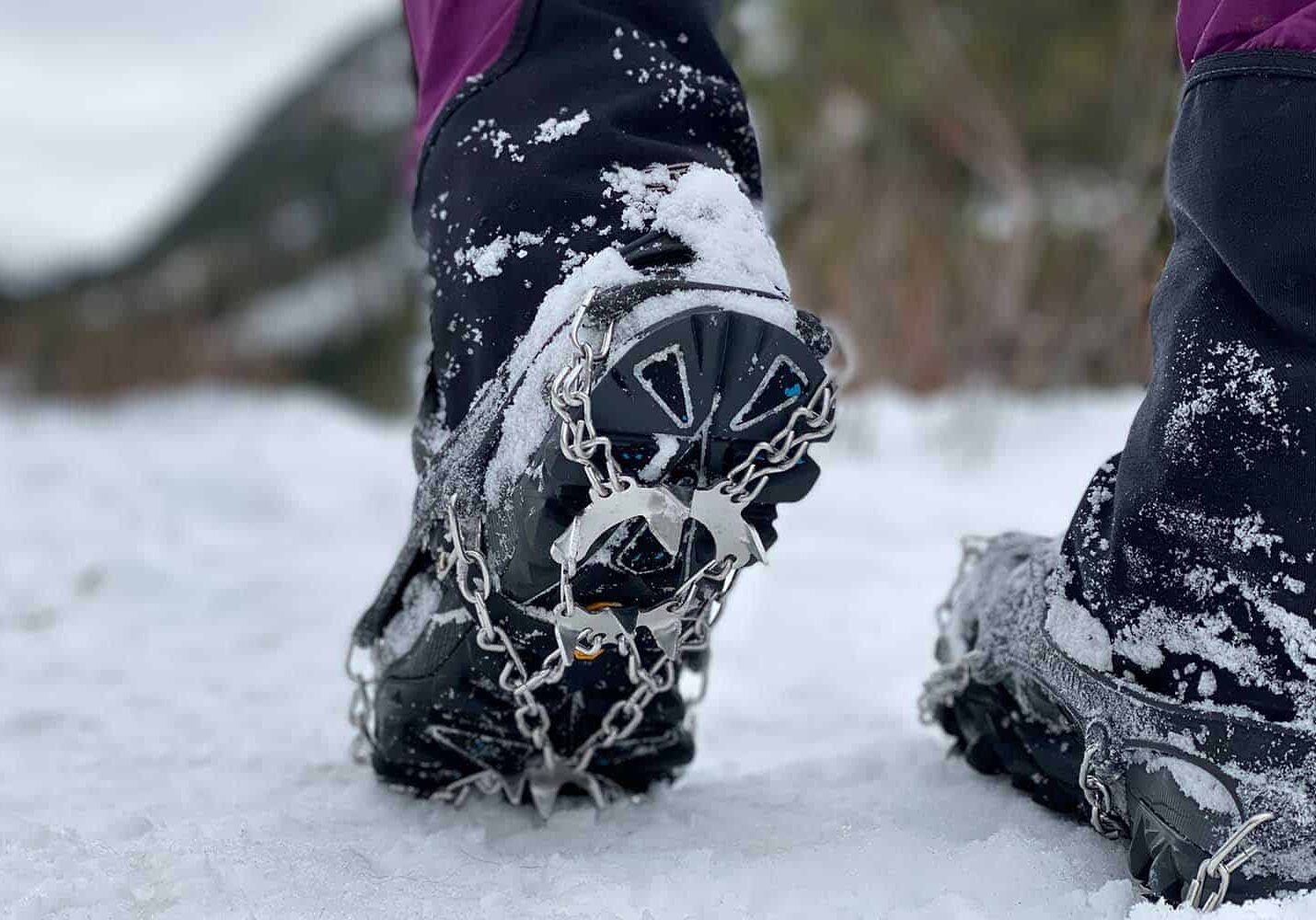 Closeup of person walking on ice, wearing shoes with snow chains and spikes