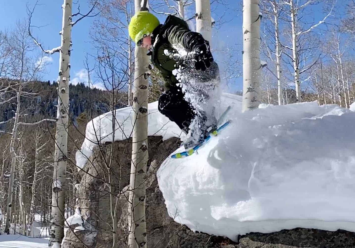 Young boy outdoors, jumping off rocks covered in snow