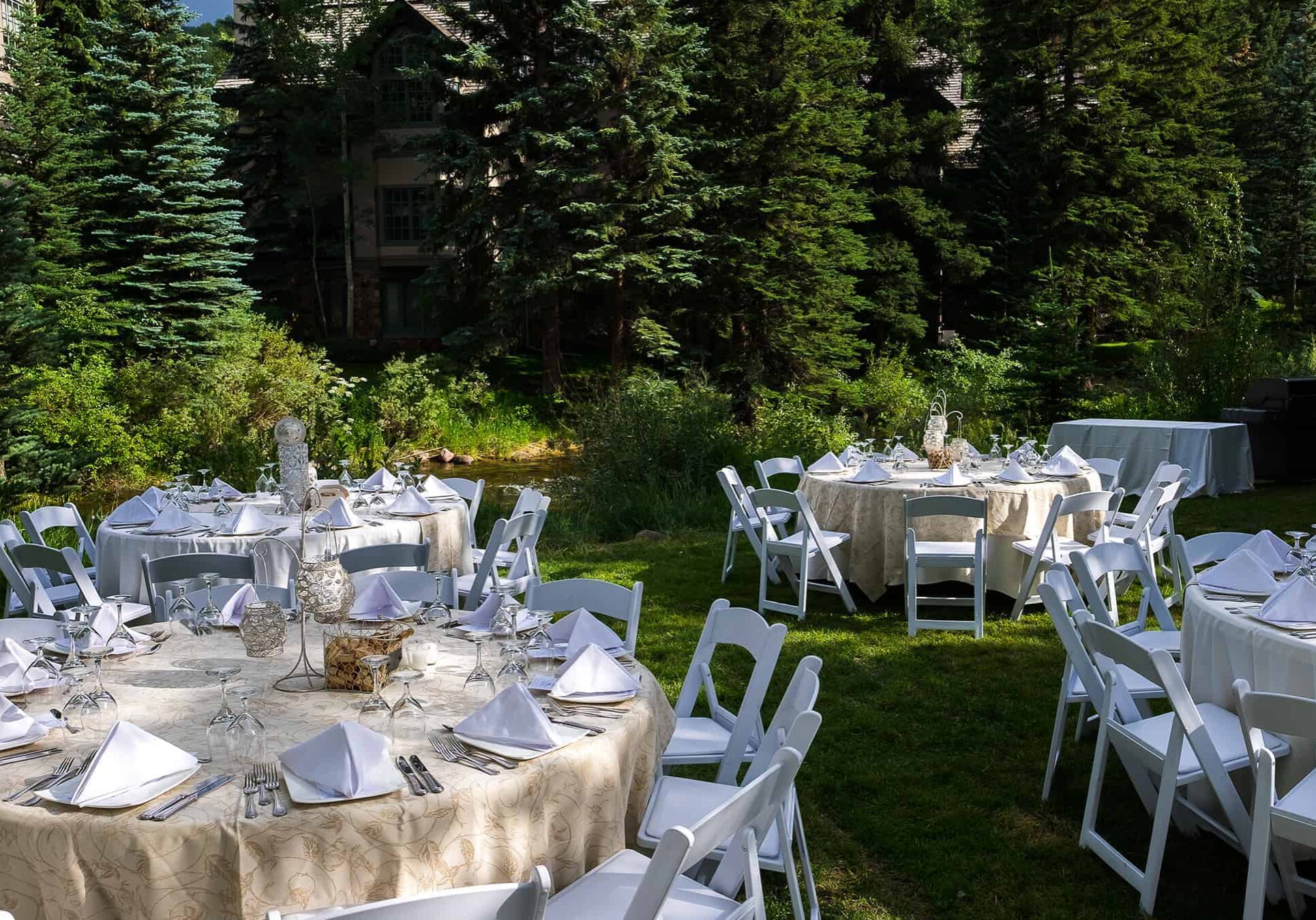 Reception tables outdoors, on grass, with placesettings