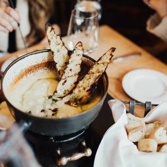 overhead view of cheese fondue pot and bread basket