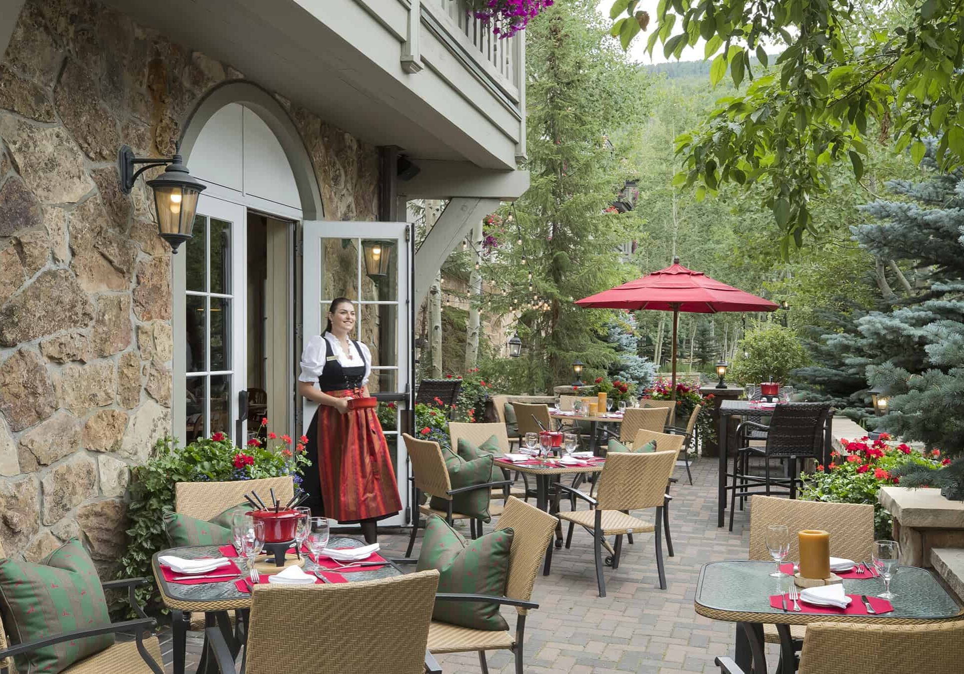 Sonnenalp Swiss Chalet outdoor patio with tables, chairs, and woman wearing dirndl carrying pot