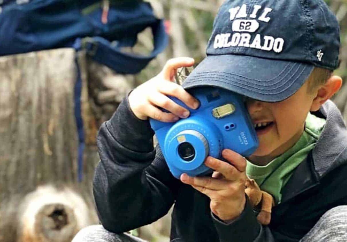 Child wearing a baseball hat taking a photo