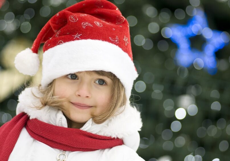Young girl wearing a Santa hat, winter coat, and scarf