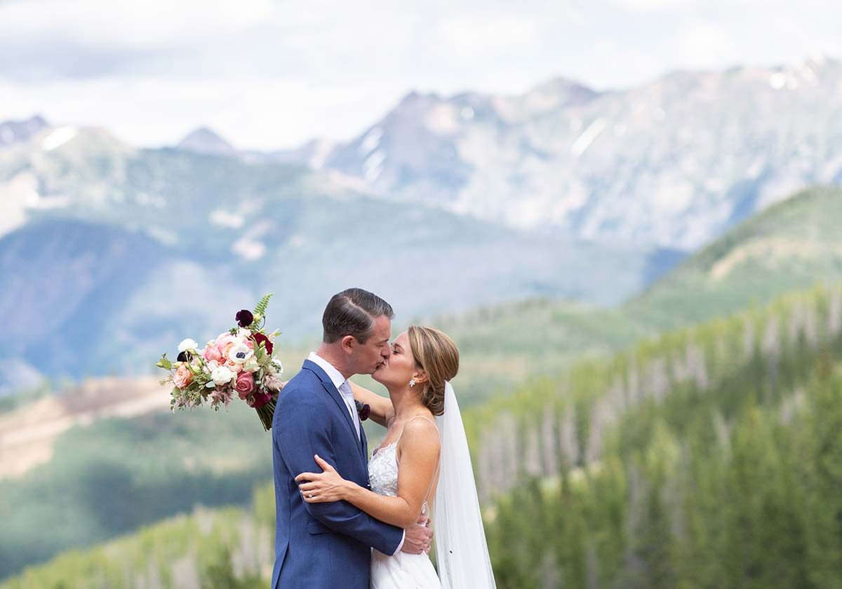 Bride and groom sharing a kiss outdoors, moutains in the background