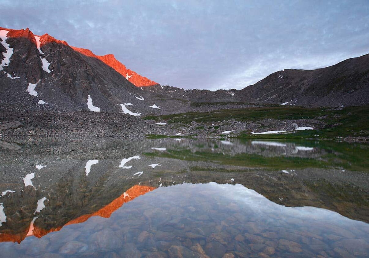 Mountain peaks at sunset reflected on shallow body of water