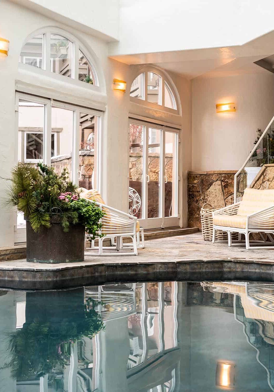Indoor pool area with patio furniture and large glass doors leading to an outdoor area